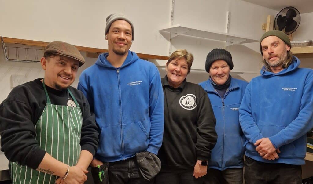 Five people in kitchen smiling
