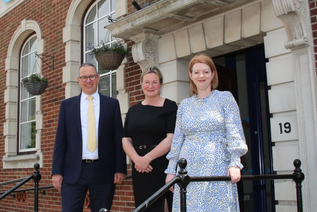 A man in a suit and two women outside a building