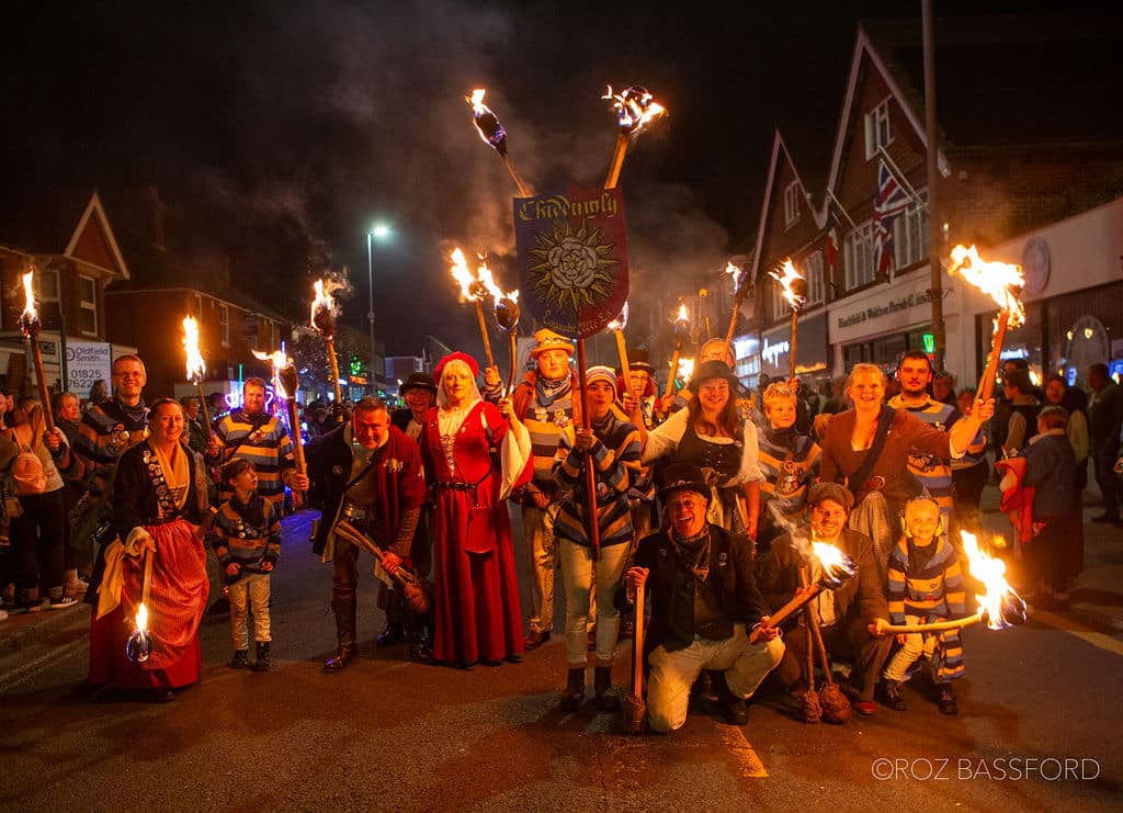 lots of people dressed up in traditional costumes with striped jumpers and fire brands in their hands in a posed image